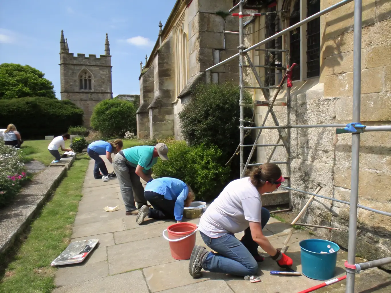 A diverse group of volunteers working together on a cultural heritage restoration project, showcasing intercultural collaboration and preservation efforts.